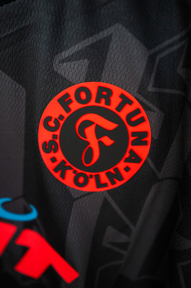 Nahaufnahme des Fortuna Köln Logos in Rot-Schwarz.