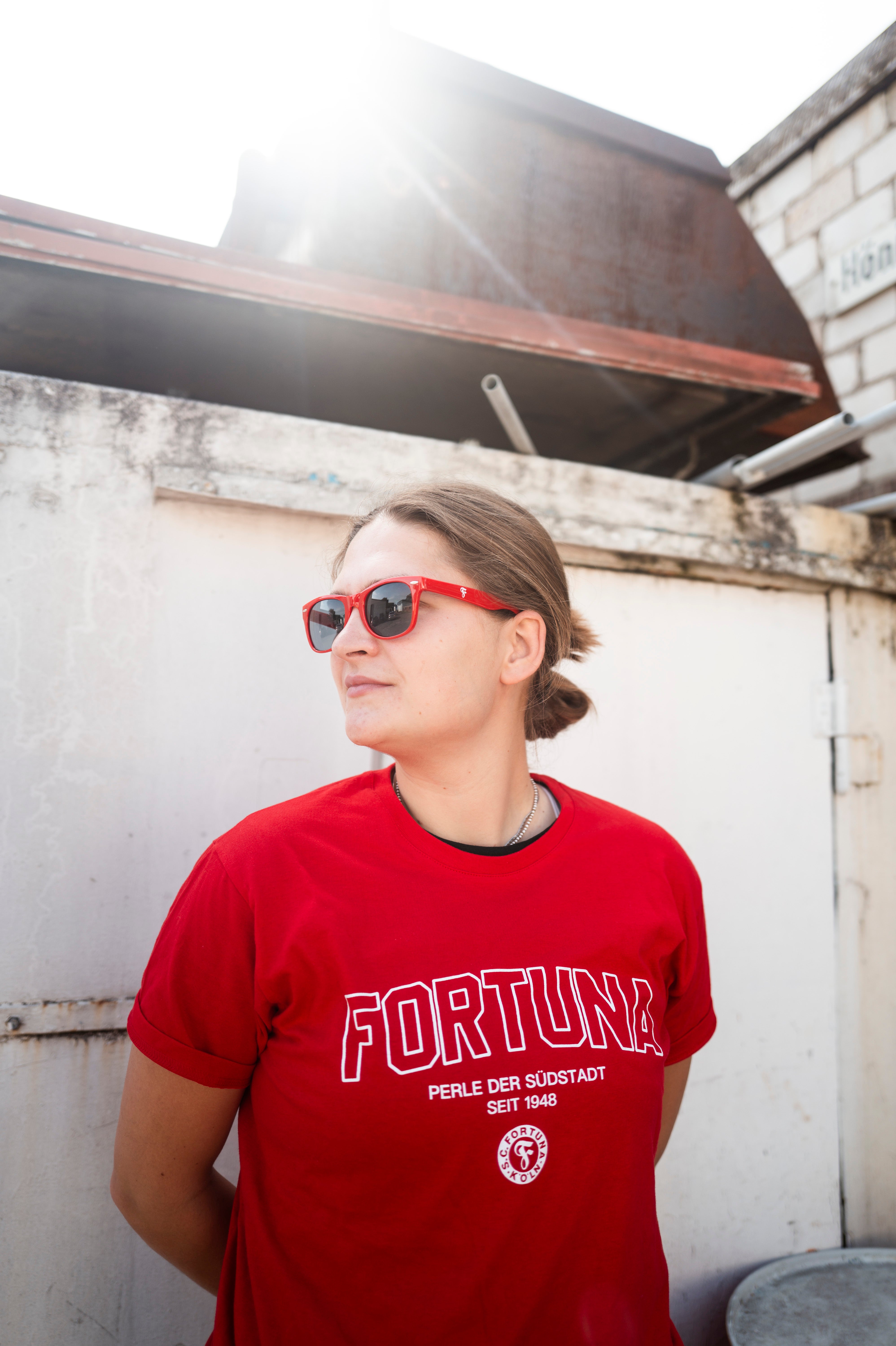 Person trägt eine rote Sonnenbrille mit Fortuna-Logo und ein rotes T-Shirt mit weißem „FORTUNA“-Schriftzug sowie Vereinslogo