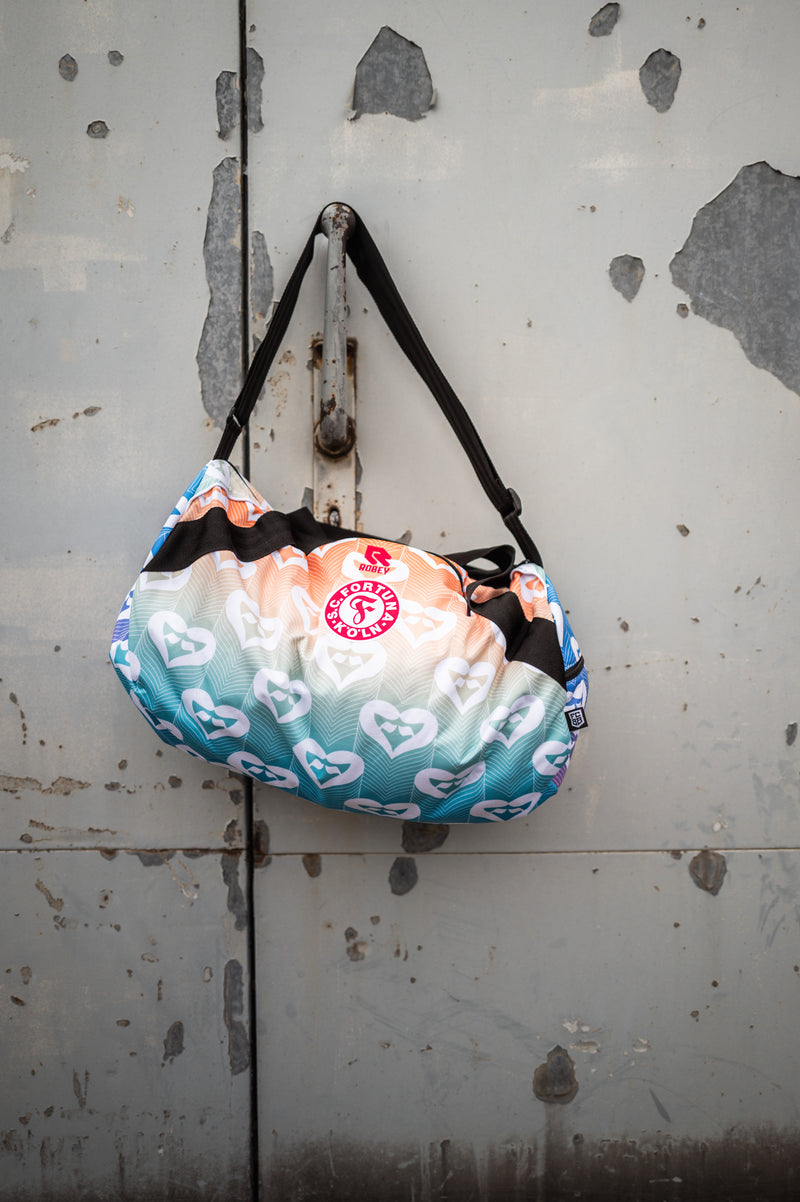 Auf dem Bild hängt die Pride Tasche einem Hacken an einer Grauen Metalltür.