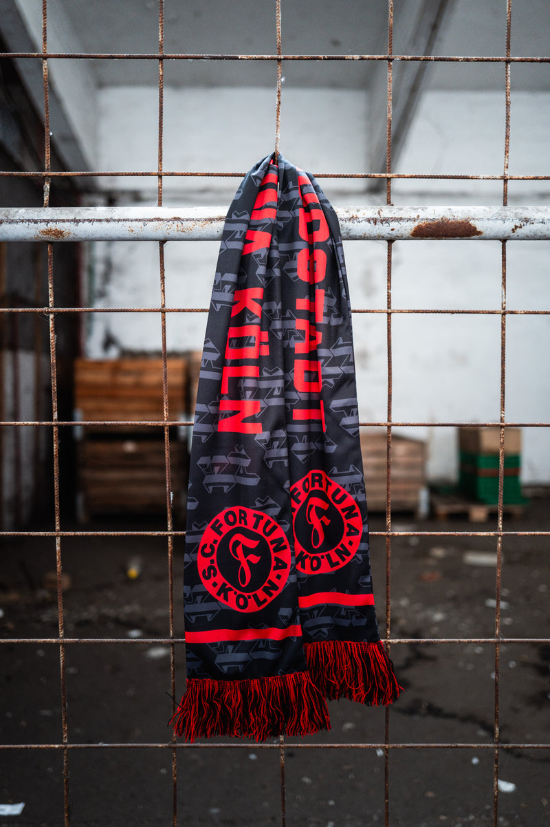 schwarz-roter Schal hängt an einem Zaun.