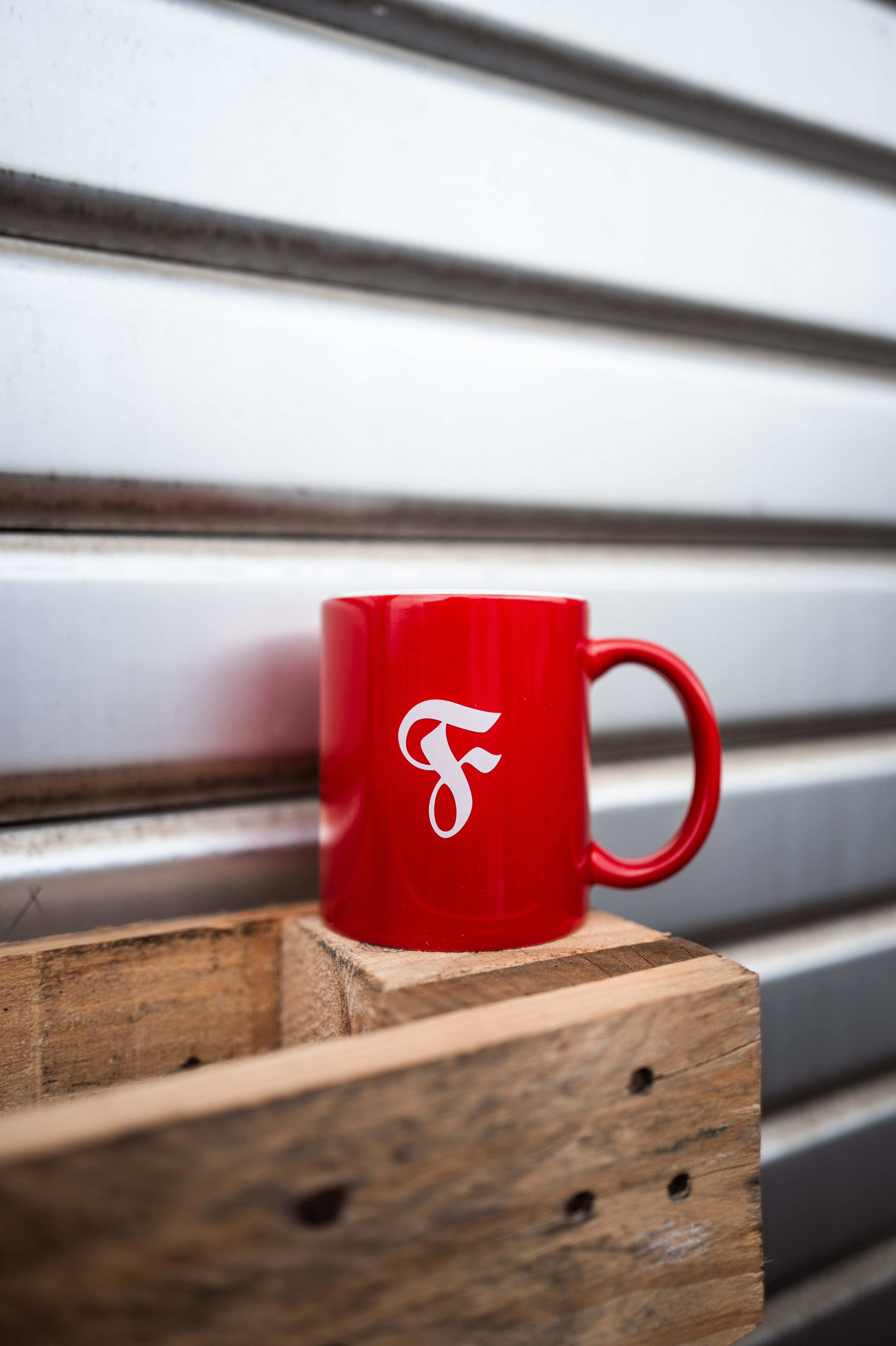 Rote Tasse steht auf Holzpalette vor Garagentor.