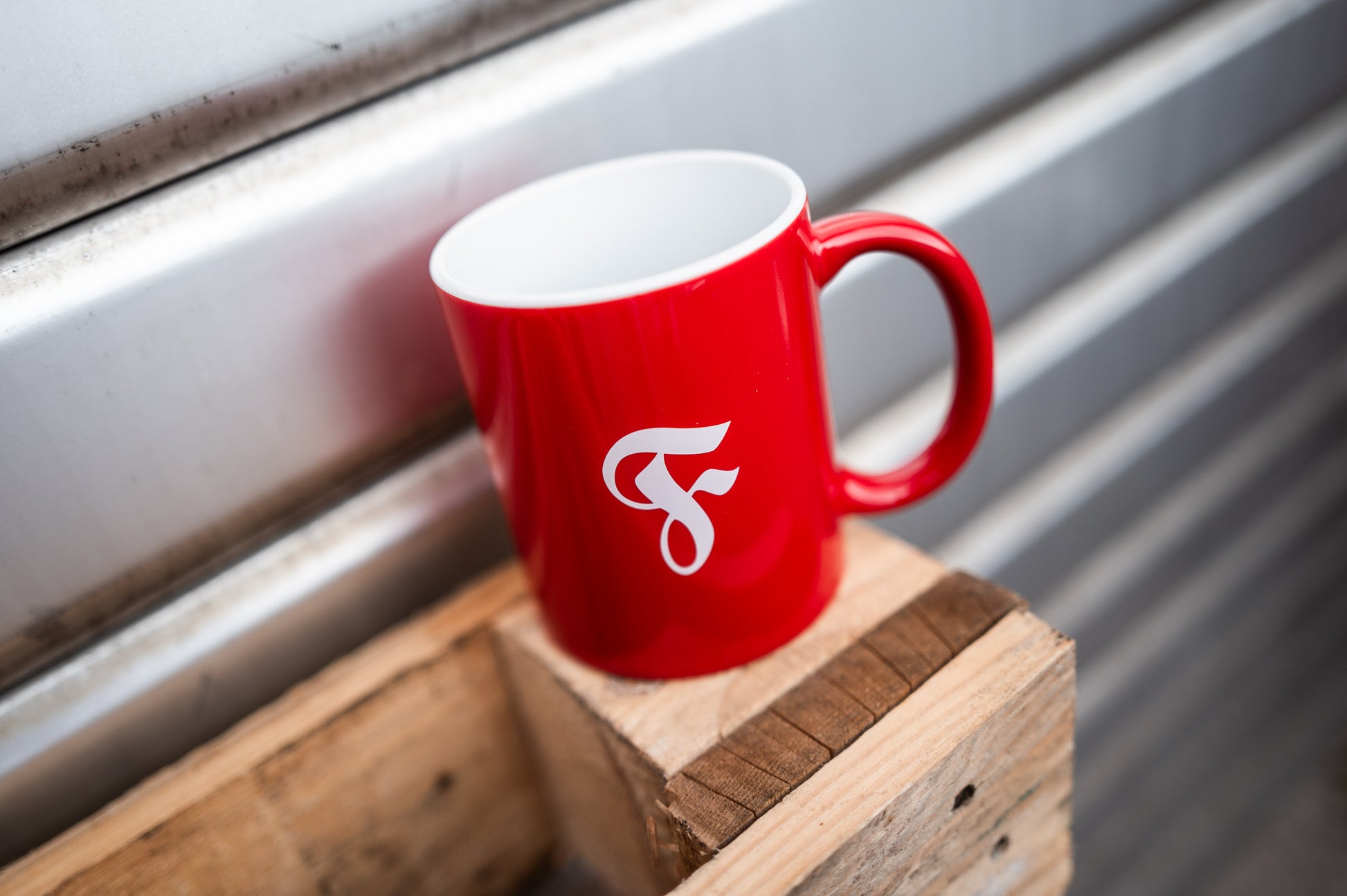 Rote Tasse steht auf Holzpalette vor Garagentor.
